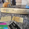 Custom gold metallic desk name plate with CEO title and business logo, displayed with matching business cards.