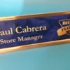 Personalized Custom blue and gold engraved name plate with store manager title and business logo, displayed on a bright blue background.